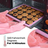 Pink silicone gloves taking a hot tray of cookies out of the oven