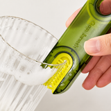 Hand using the green brush to scrub the inside of a soapy glass