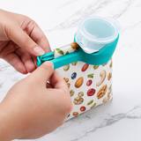 Hands clipping the green sealer onto an open snack bag