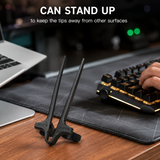 Black finger chopsticks standing upright on a desk beside a keyboard