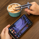 Hand using grey finger chopsticks to take crisps while holding a phone