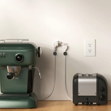 Cable clips holding coffee machine and toaster cords against a wall